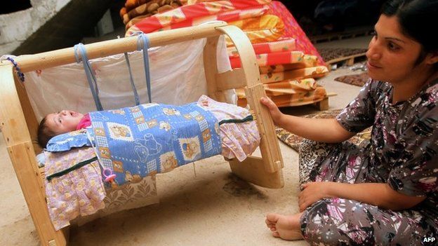 An Iraqi woman from the Yazidi community sits near her baby