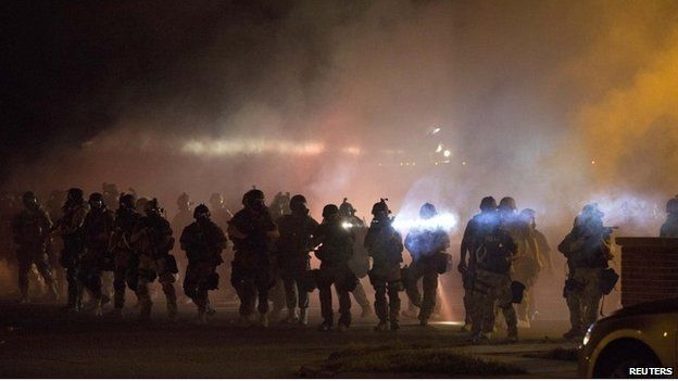 Heavily armed riot police clear demonstrators from a street in Ferguson, Missouri - 13 August 2014
