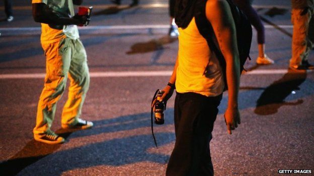 A young man carrying what appears to be a Molotov cocktail on the streets of Ferguson, Missouri - 13 August 2014
