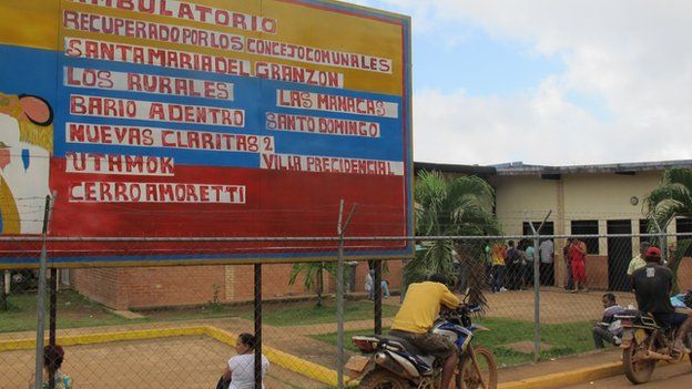 Rural hospital building with large handpainted sign in foreground