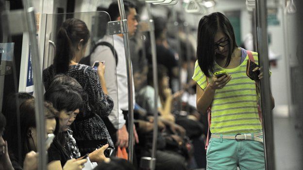 People checking phones on Singapore train