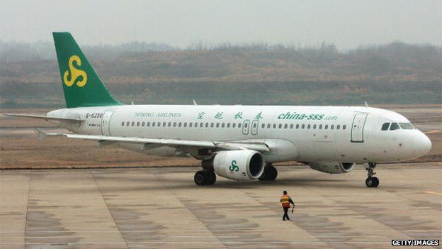 A worker directs an airplane from Spring Airlines at the Nanjing Airport on 8 February 2007 in Nanjing of Jiangsu Province, China