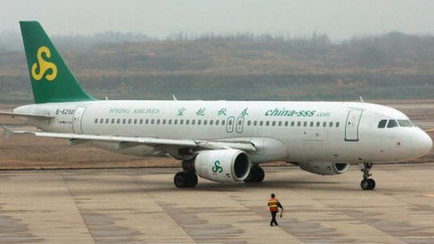A worker directs an airplane from Spring Airlines at the Nanjing Airport on 8 February 2007 in Nanjing of Jiangsu Province, China