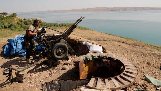 A Kurdish peshmerga fighter prepares his weapon at his combat position near the Mosul Dam at the town of Chamibarakat outside Mosul, Iraq, Sunday, Aug 17