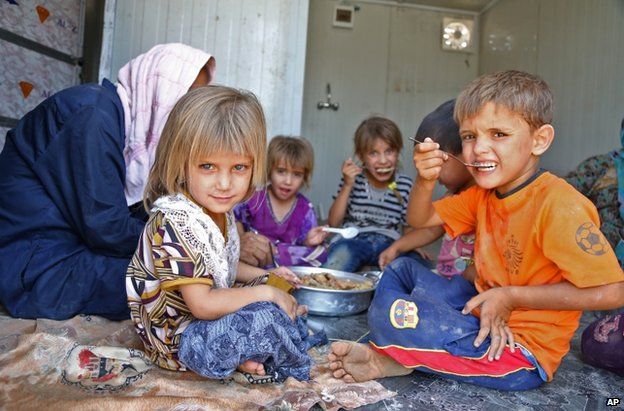 Shia Muslim refugees from Mosul eat at a refugee camp in Baghdad, 17 August