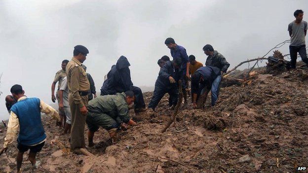 Indian residents and security personnel dig through mud following heavy rainfall and landslides in the Pauri district of the state of Uttarakhand on August 15, 2014