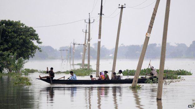 Indian villagers paddle a boat through floodwaters over submerged roads in Balimukh village in the Morigaon district of Assam state on August 17, 2014