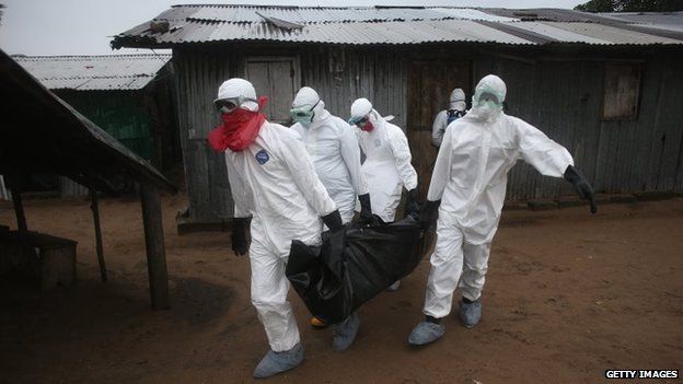 A Liberian burial team wearing protective clothing retrieves the body of a 60-year-old Ebola victim from his home on August 17, 2014 near Monrovia, Liberia.