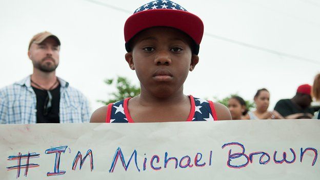 A protestor stands outside a church in Ferguson, Missouri, holding a sign reading "I'm Michael Brown"