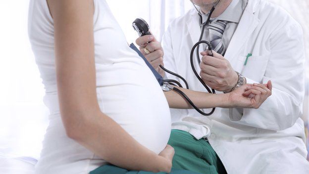 Doctor examining pregnant woman (posed by model)