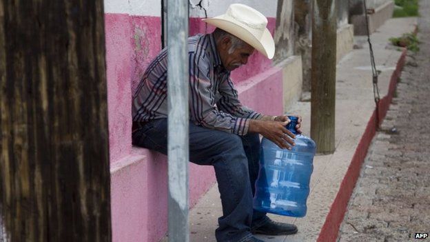 A resident waits for drinking water in the Arizpe community on 12 August, 2014