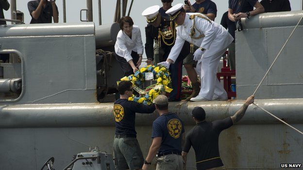 US and naval officials pass a wreath to Sailors assigned to Mobile Diving Salvage Unit (MDSU) 1 during a wreathe laying ceremony for the sunken Navy vessel USS Houston (CA 30) 12 June 2014