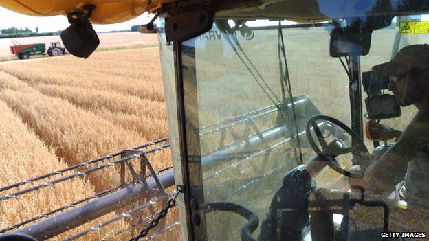 A French farmer harvests an oat field on a combined harvester using GPS