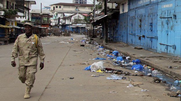 A Liberian soldier walks along a deserted street with shops closed in Monrovia, Liberia