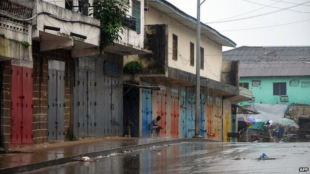 A lone man sits outside shops that were closed in Monrovia's West Point slum