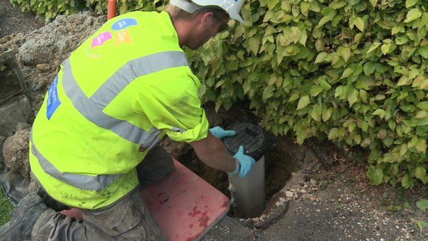 Workman installing water meter in road