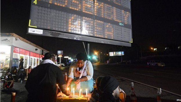 Demonstrators light candles while taking a break from walking at the approved assembly area set up for them while they protest the shooting death of Michael Brown in Ferguson, Missouri, USA, late 20 August 2014