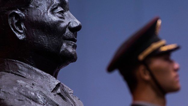 A soldier stands in front of a sculpture featuring former Chinese leader Deng Xiaoping during the Exhibition of the 110th anniversary of the birth of Deng Xiaoping on 21 August, 2014 in Hong Kong