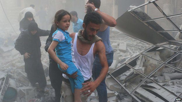 A Syrian man carries a girl amid debris following a air strike by government forces in the northern city of Aleppo on 15 July
