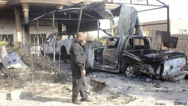 An Iraqi security officer stands next to the wreckage of a vehicle belonging to the Islamic State in Diyala province, 12 August 2014