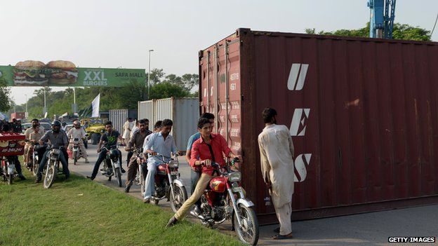 People on motorbikes getting past shipping containers
