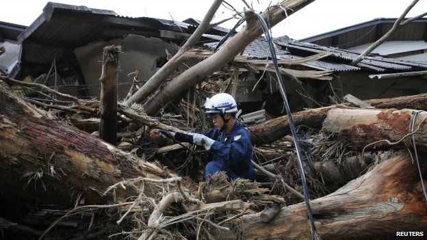 A policeman searches for survivors at a site where a landslide swept through a residential area at Asaminami ward in Hiroshima (23 August 2014)