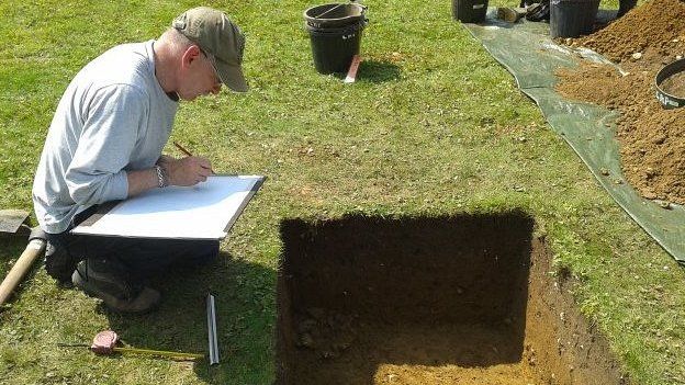 Archaeologist records details of an excavated pit