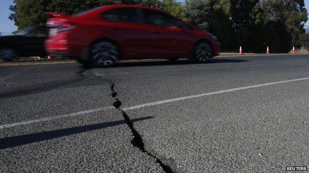 A car drives over cracked asphalt along Highway 12 after a 6.0 earthquake in Napa, California (24 August 2014)