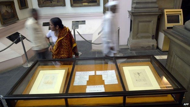Indian visitors walk past displays of two artworks by Salvador Dali in Durbar Hall of The Victoria Memorial in Kolkata on August 14, 2014