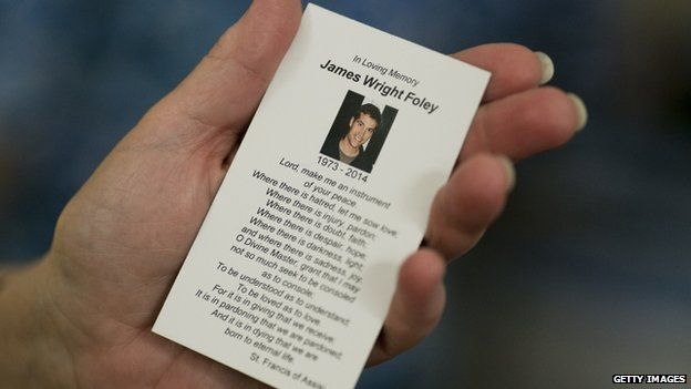 parishioner holds a prayer card in memory of James Foley after a Catholic mass in Rochester, New Hampshire