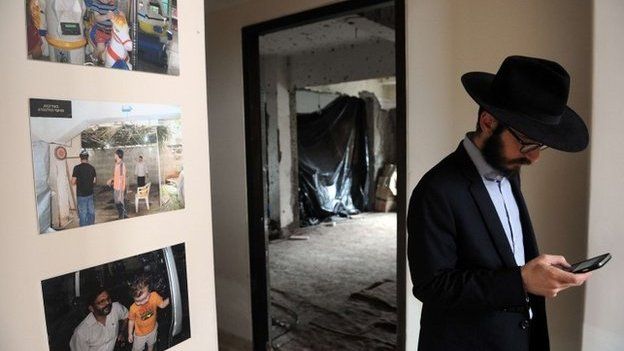 A rabbi stands alongside photographs of Rabbi Gavriel Holtzberg at Nariman (Chabad) House in the Indian city of Mumbai on August 26, 2014