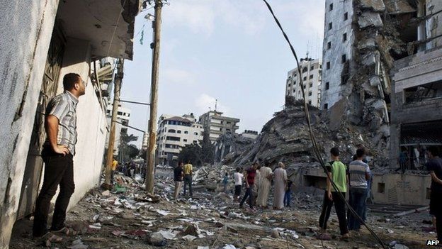 Palestinians look at a high-rise building in Gaza City that targeted in an Israeli air strike on 26 August 2014