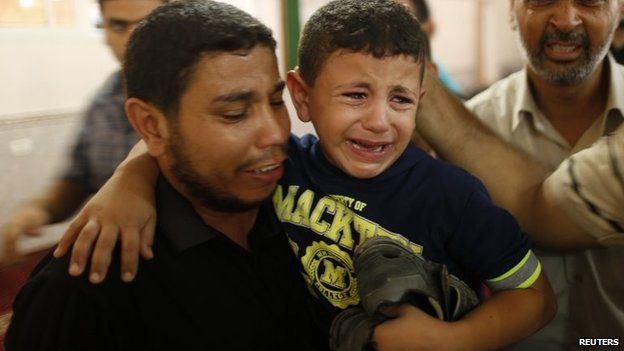 A Palestinian boy is comforted during the funeral for his father Mohammed Abu Ajwa, a Hamas militant, who was killed in an Israeli air strike (26 August 2014)