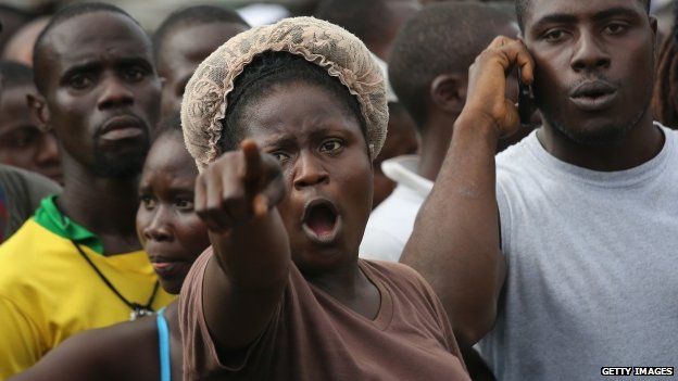 Angry people quarantined in the West Point township in Liberia's capital, Monrovia, wait for relatives to deliver them food and personal items - 23 August 2014