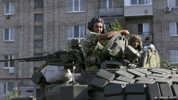 Pro-Russian rebels ride on a tank in the town of Krasnodon, eastern Ukraine, Sunday, Aug. 17, 2014. A column of several dozen heavy vehicles, including tanks and at least one rocket launcher, rolling through rebel-held territory on Sunday