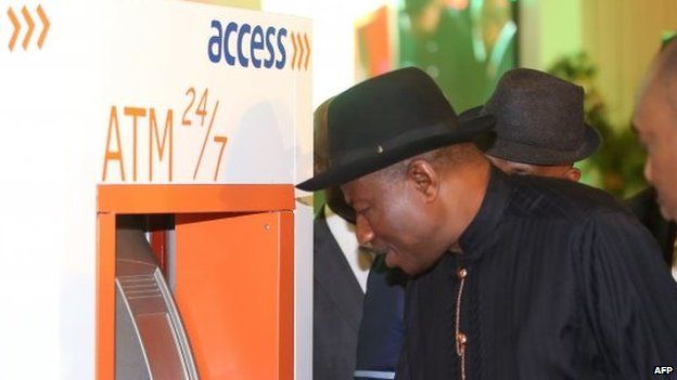 Nigerian President Goodluck Jonathan tries to make cash withdrawal with his electronic identity card during the launching of the cards in Abuja on 28 August 2014