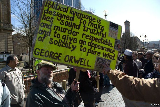 Protest banner quoting George Orwell: "Political language is designed to make lies sound truthful and murder respectable and to give an appearance of solidity to pure wind."