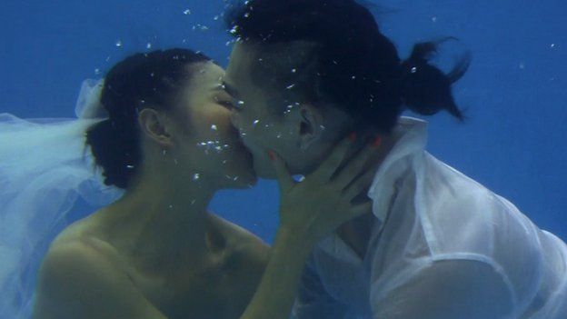 bride and goom kissing underwater