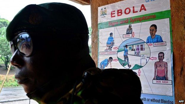 A soldier from the Sierra Leone army stands near an Ebola information poster outside Kailahun, on August 14, 2014.