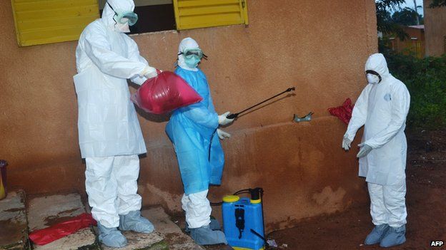 Health workers take off their protective suits after finishing disinfecting areas at the Pita hospital on August 25, 2014