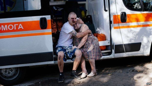An injured man hugs a woman as they sit in ambulance after a shelling attack on Donetsk (23 August 2014)