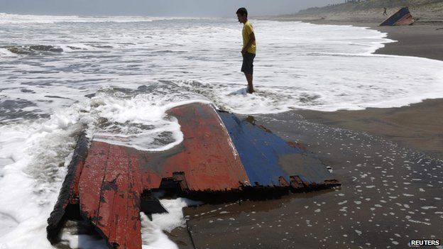 A youth stands near a piece of wreckage of a boat which Indonesian police said was carrying migrants to Australia and sank off the Indonesian coast, at Agrabinta beach on the outskirts of Sukabumi, Indonesia"s West Java province in this September 28, 2013