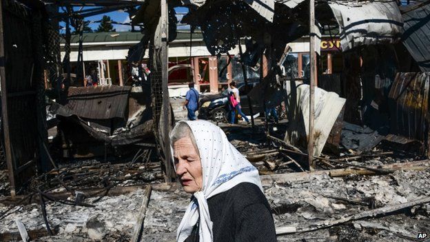 A woman passes by shops destroyed by shelling in Donetsk, eastern Ukraine. Photo: 30 August 2014