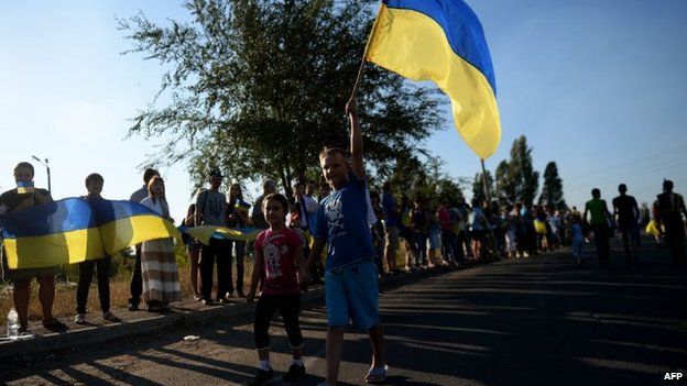Ukrainian loyalists hold their flag as they rally at the last checkpoint on the eastern side of Mariupol (picture from 30 August)