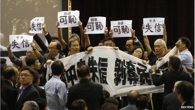 Pro-democracy lawmakers hold up a banner and placards to protest as Li Fei (not pictured), deputy general secretary of the National People's Congress (NPC) standing committee, speaks during a briefing session in Hong Kong 1 September 2014.
