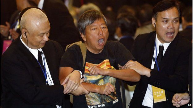 Pro-democracy lawmaker Lee Cheuk Yan (centre) is taken away by security guards after a protest against Li Fei, deputy secretary general of the National People's Congress" Standing Committee, in Hong Kong Monday, 1 Sept 2014.