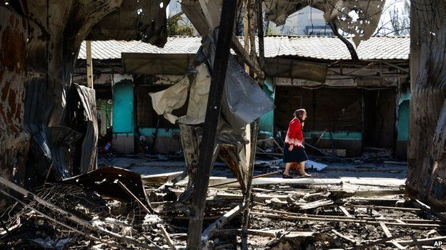 Woman walks past damaged buildings in Donetsk (30 August 2014)