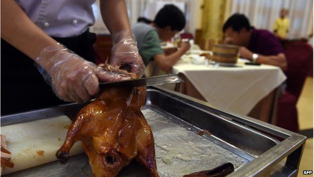 This photo taken on 24 July 2014 shows a chef slicing Peking Duck for diners at the Quanjude restaurant in Beijing.