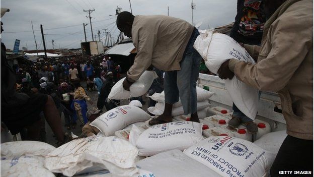 Residents of the West Point slum in Monrovia, Liberia, receive food aid on 21 August 2014.