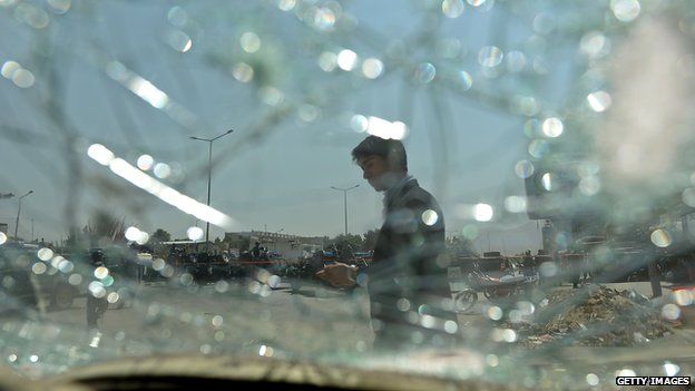 An Afghan bystander is seen through broken glass of car at the site of a suicide attack in Kabul on 10 August 2014.